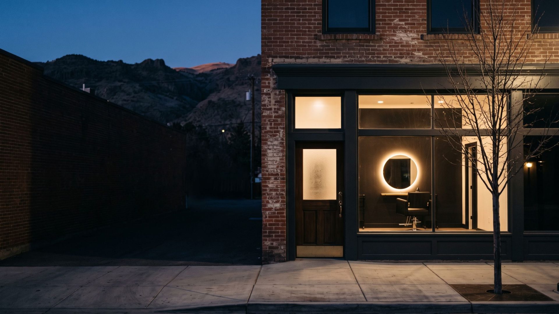 A beauty salon in a Midtown Reno brick storefront at dusk, Sierra foothills behind
